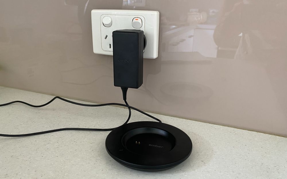 https://huntingwaterfalls.com/wp-content/uploads/2021/03/ember-mug-charging-coaster-plugged-into-wall-socket-turned-on-switch.jpg